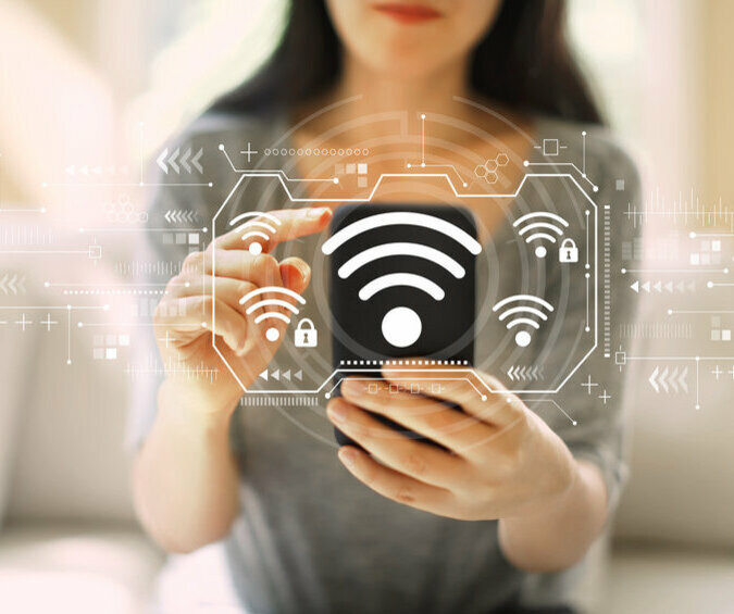 WLAN-Zeichen vor einer Frau, die ihr Smartphone bedient.
