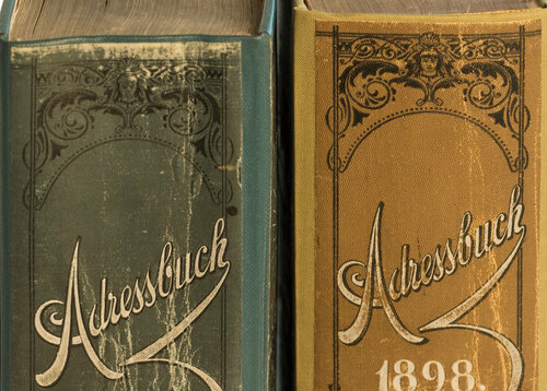 Zwei historische Adressbücher stehen mit dem Buchrücken  nach vorne nebeneinander.