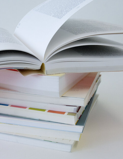 Bücherstapel mit aufgeschlagenem Buch