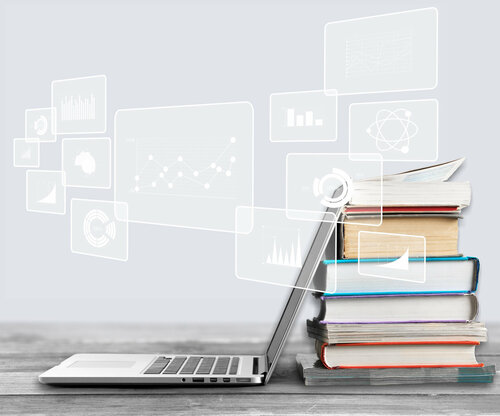 Ein Laptop lehnt an einem Bücherstapel