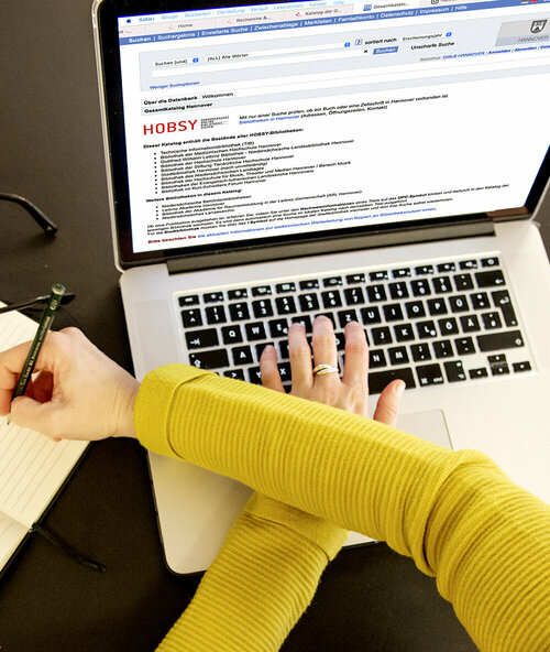 Hände auf einer Tastatur. Recherche im Gesamtkatalog.