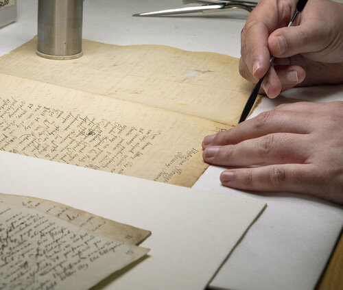 Zwei Hände restaurieren eine Handschrift aus dem Leibniz-Nachlass