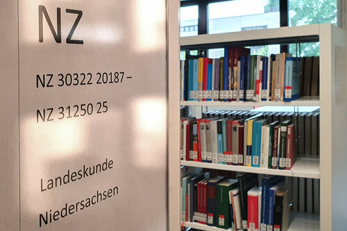 Auf der linken Seiten steht eine Information mit dem Themenbereich. Hier NZ für "Niedersachsen". Im Hintergrund steht ein Bücheregal.