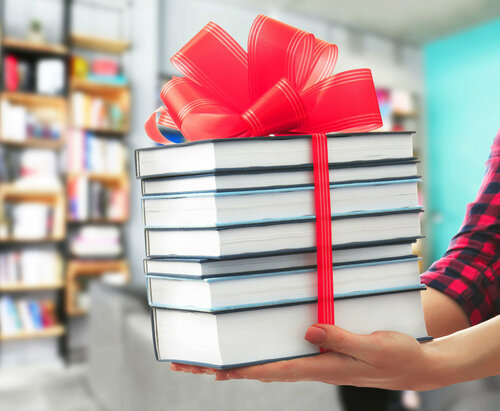 Ein Bücherstapel mit einer großen, roten Geschenkschleife verpackt.