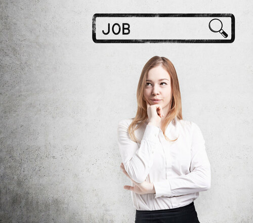 Eine junge Frau in Businesskleidung steht vor einer grauen Wand. Über dem Kopf ist eine Suchschlitzgrafik mit dem Begriff Job eingebaut.