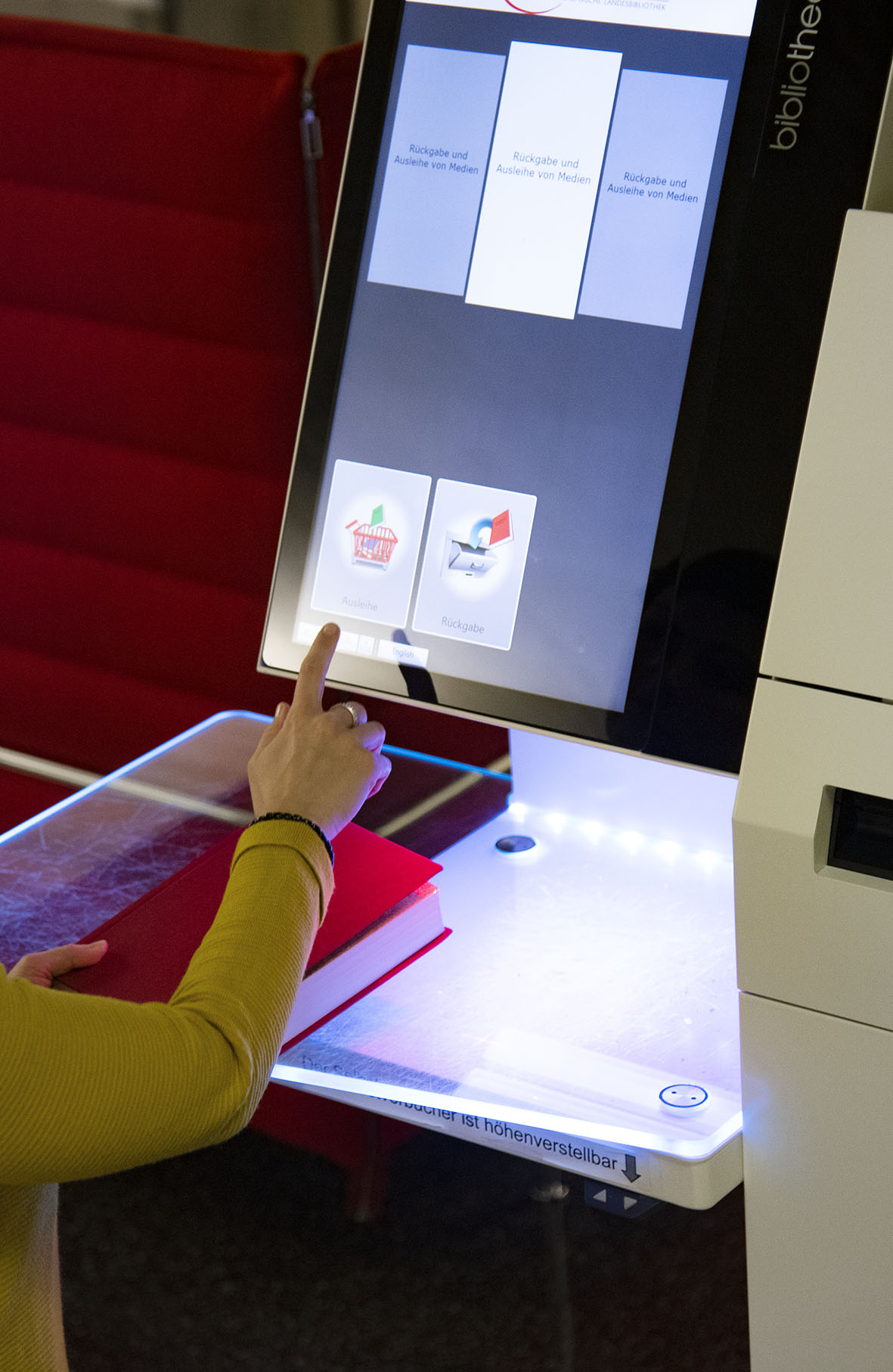 Eine Person, die per Touchscreen die Selbstverbucheranlage benutzt.